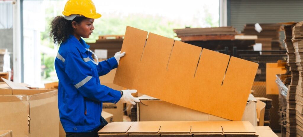 Trabajadora de un centro de reciclaje manipulando cartón